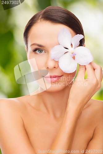 Image of relaxed woman with orchid flower over eye