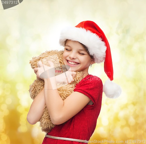 Image of smiling girl in santa helper hat with teddy bear