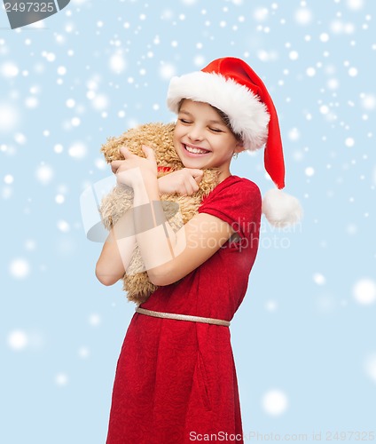 Image of smiling girl in santa helper hat with teddy bear