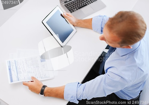 Image of businessman with tablet pc and papers in office