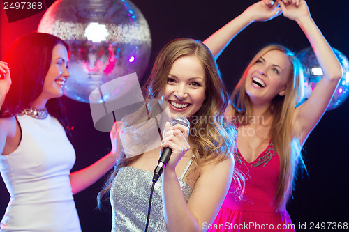 Image of three smiling women dancing and singing karaoke