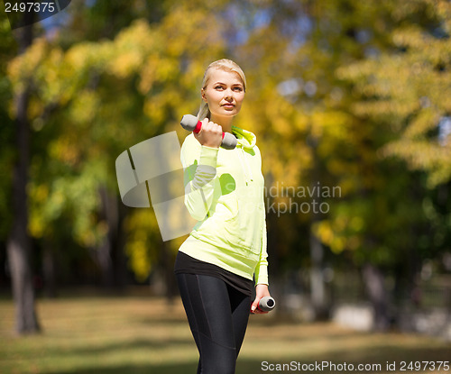 Image of sporty woman with light dumbbells outdoors