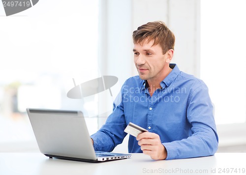 Image of man with laptop and credit card at home