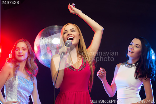 Image of three smiling women dancing and singing karaoke