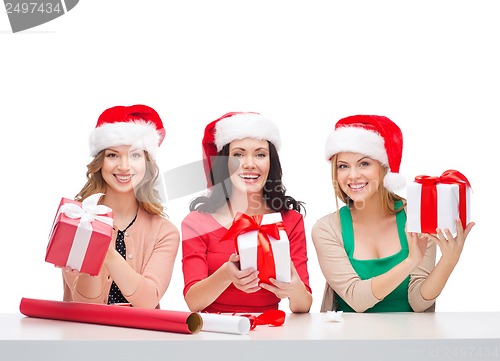 Image of smiling women in santa helper hats with gift boxes