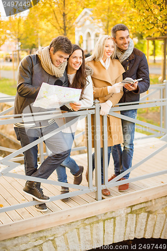 Image of couples with tourist map in autumn park