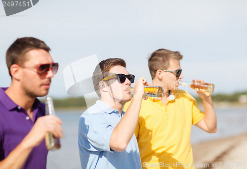 Image of friends on the beach with bottles of drink
