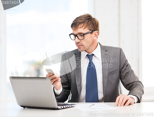 Image of businessman working with laptop and smartphone