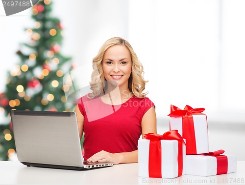 Image of woman with gift boxes and laptop computer