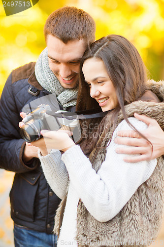 Image of couple with photo camera in autumn park