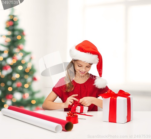 Image of smiling girl in santa helper hat with gift box