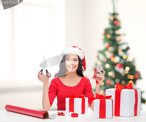 Image of woman in santa helper hat with many gift boxes