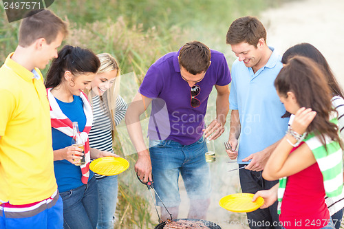 Image of group of friends having picnic on the beach