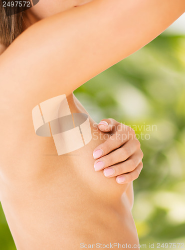 Image of woman checking breast for signs of cancer