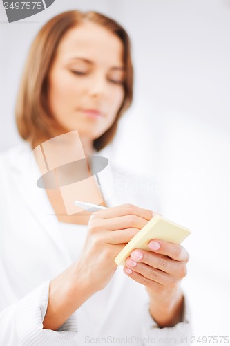 Image of businesswoman writing on sticky note