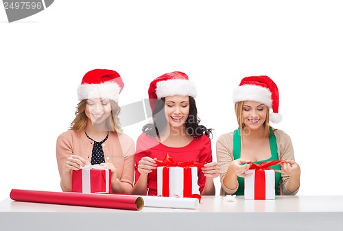 Image of smiling women in santa helper hats with gift boxes