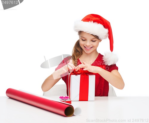 Image of smiling girl in santa helper hat with gift box