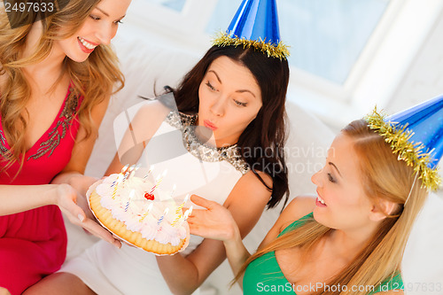 Image of three women wearing hats holding cake with candles