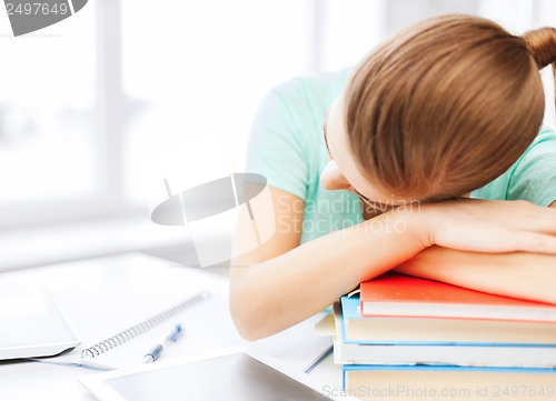 Image of tired student sleeping on stock of books