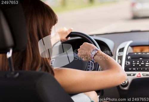 Image of woman driving a car and looking at watch