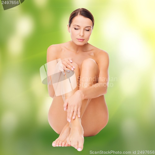 Image of beautiful naked woman touching her legs