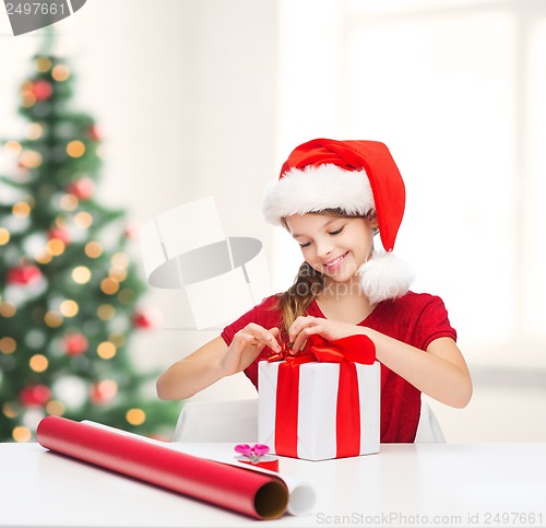 Image of smiling girl in santa helper hat with gift box