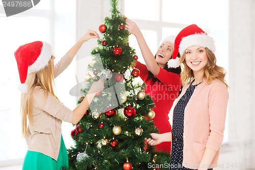 Image of women in santa helper hats decorating a tree