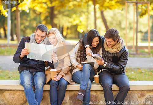 Image of couples with tourist map in autumn park