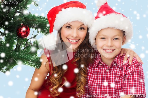 Image of happy mother and child boy in santa helper hats