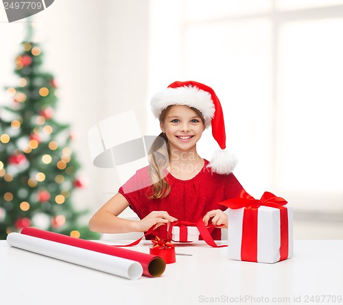 Image of smiling girl in santa helper hat with gift box