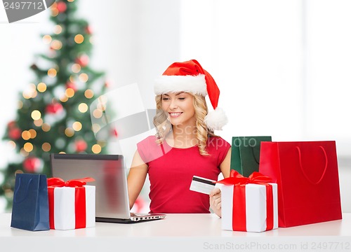 Image of woman with gifts, laptop computer and credit card