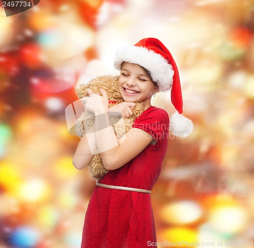 Image of smiling girl in santa helper hat with teddy bear