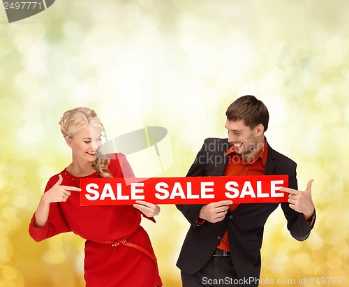 Image of smiling woman and man with red sale sign