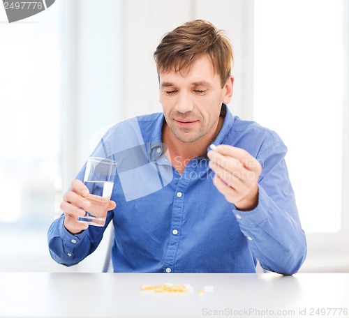 Image of ill man taking his pills at home