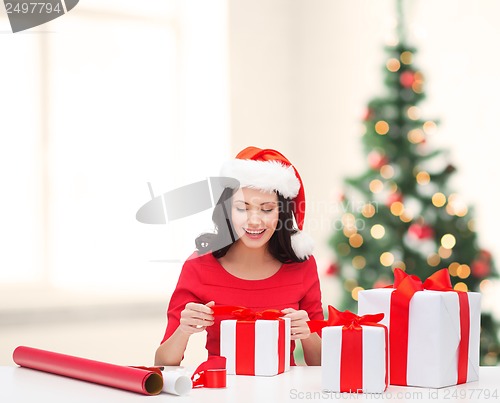 Image of woman in santa helper hat with many gift boxes