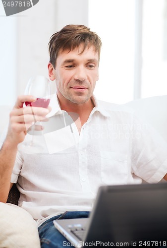 Image of man with laptop computer and glass of rose wine