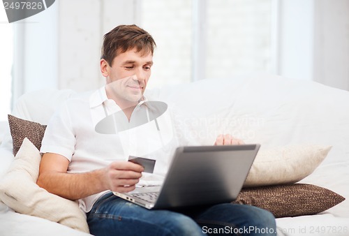 Image of man with laptop and credit card at home