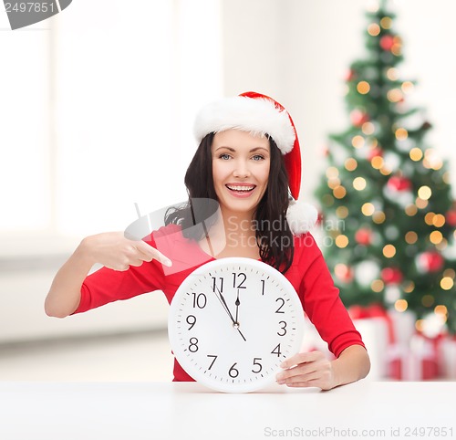 Image of woman in santa helper hat with clock showing 12