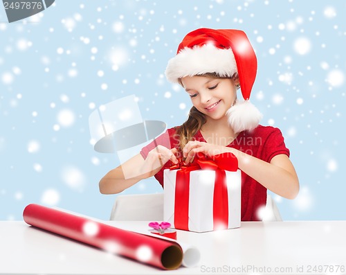 Image of smiling girl in santa helper hat with gift box