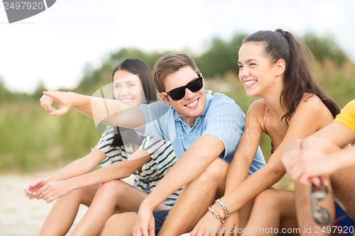 Image of group of friends pointing somewhere on the beach