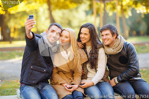 Image of group of friends with photo camera in autumn park