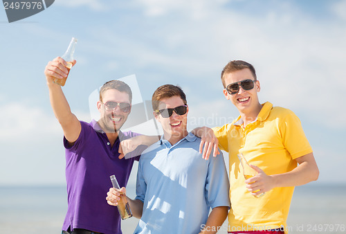 Image of friends on the beach with bottles of drink