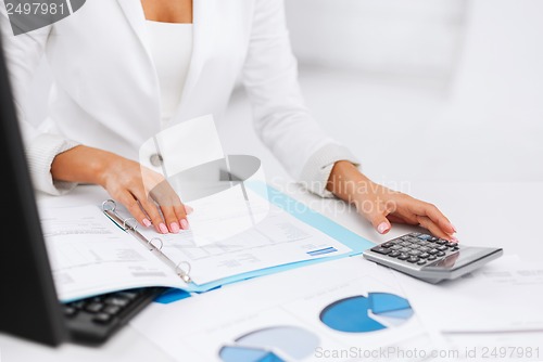 Image of woman hand with calculator and papers