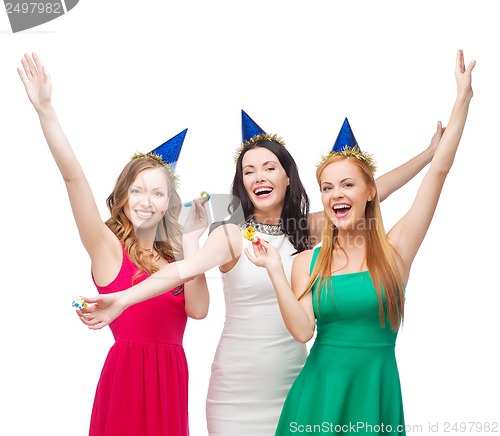 Image of three smiling women in hats blowing favor horns