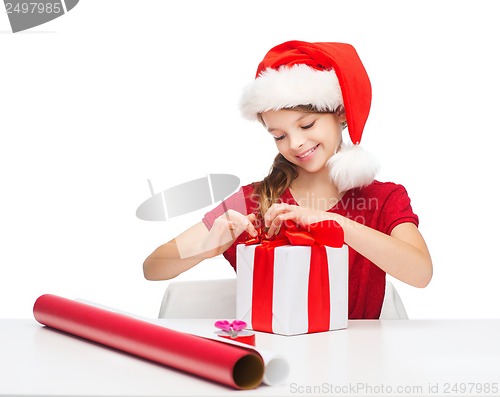 Image of smiling girl in santa helper hat with gift box