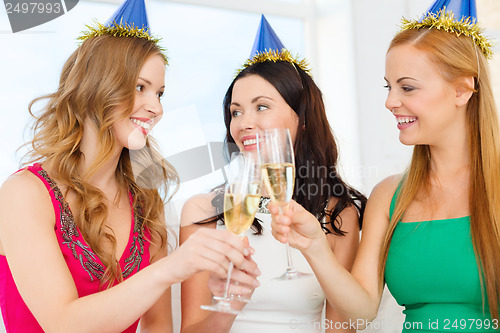 Image of three women wearing hats with champagne glasses