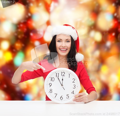 Image of woman in santa helper hat with clock showing 12