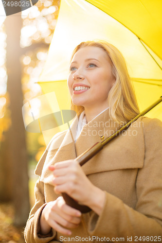 Image of woman with yellow umbrella in the autumn park