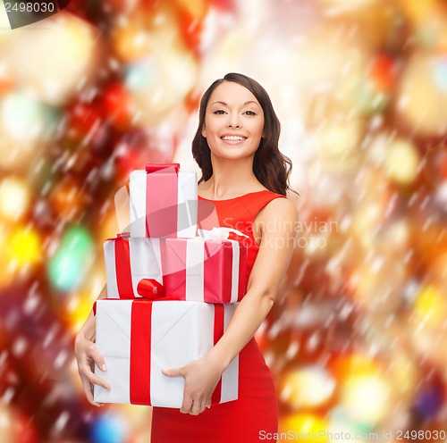 Image of smiling woman in red dress with many gift boxes
