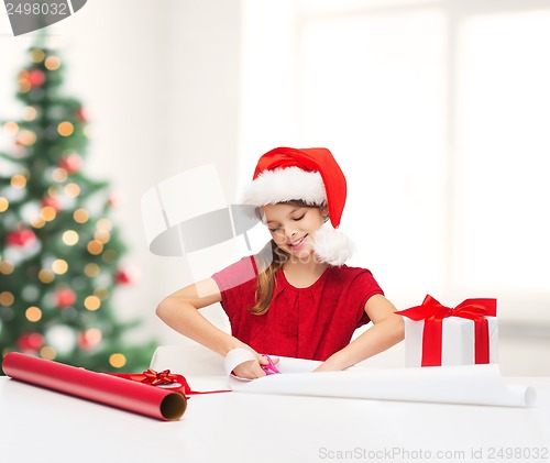 Image of smiling girl in santa helper hat with gift box